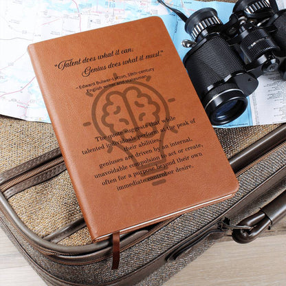 Notebook journal with cover quote: Edward Bulwer-Lytton's "Talent does what it can; Genius does what it must." black text layered on a lightbulb on the brown vegan leather cover laying on a suitcase with binoculars.